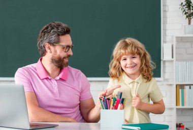 Bir okul çocuğuyla öğretmen. Öğretmen ve öğrenciler sınıfa. İlkokul öğrencisinin dersi var. Öğretmeni olan çocuk İngilizce ya da matematik öğreniyor.