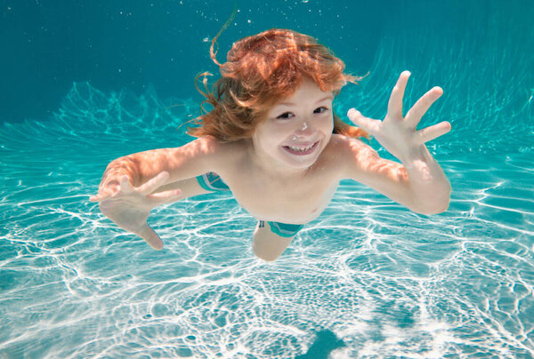 Child underwater. Funny face portrait of child boy swimming and diving underwater with fun in pool