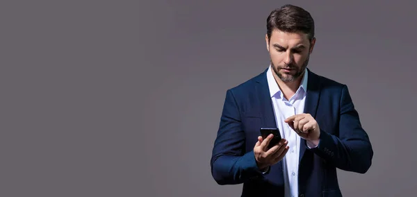 European business man in formal suit watching on mobile phone. Handsome man wearing formal wear using smart phone, type sms message. Banner for header, copy space. Poster for web design
