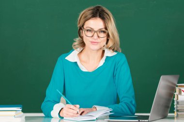 Üniversite sınıfında dizüstü bilgisayarı olan genç bir kız öğrenci. Öğrenci üniformalı kız öğrenci. Sınıfta ders çalışmak. Tahtada üniversite öğrencisi. Masadaki kız öğrenci. Öğrenci günü. Okula geri dön.