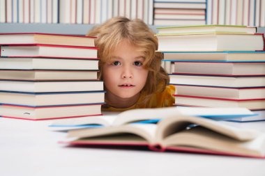 Küçük öğrenci kitap okuyor. Bir kitapçıda ya da okul kütüphanesinde kitap okuyan çocuklar