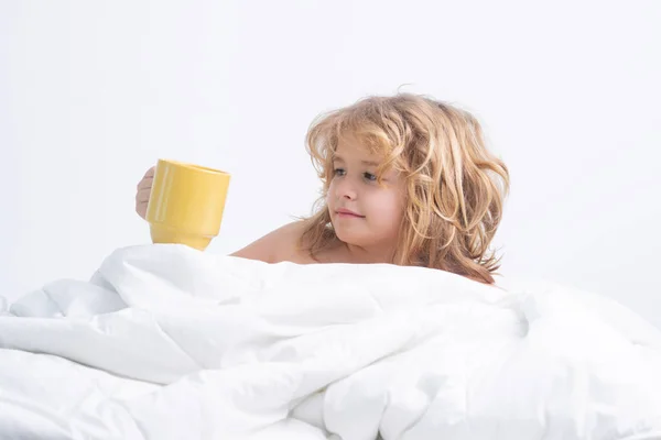 早上喝 躺在床上拿杯子的孩子小孩躺在大床上的画像 快乐孩子在家里过得很开心的概念 孩子在床上醒来 — 图库照片