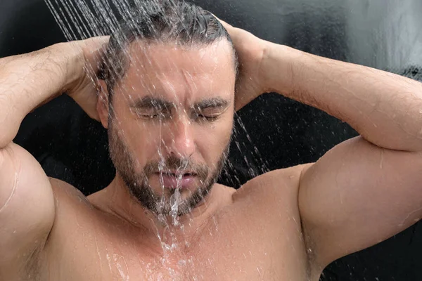 Man taking a shower. Washing hair with shampoo under water falling from shower head. Morning routine lifestyle guy showering. Body care hygiene. Shower concept. Man is under water drops in shower