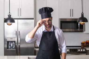Aşçı, aşçı ya da fırıncı portresi. Aşçı şapkalı ve aşçı üniformalı adam mutfakta yemek pişiriyor.