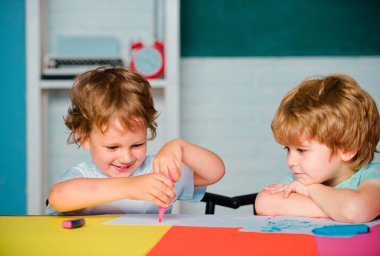 İlkokuldan erkek öğrenciler okulda resim çiziyor. Neşeli gülümseyen küçük öğrenciler eğleniyor. Mutlu sevimli zeki çocuklar.
