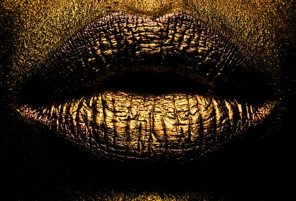 Closeup golden lips closeup. Gold metal lip. Beautiful makeup. Golden lip gloss on beauty female mouth, closeup. Sensual forms of woman lips