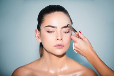 Makyaj fırçasıyla kirpiklerine siyah rimel süren bir kadın. Makyöz kaşlarını fırçalıyor. Makyajlı güzellik modeli portresi.