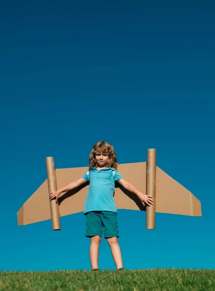 旅行の夢 空を背景におもちゃの飛行機でジェットパックを飛ぶ子供 段ボール飛行機で遊んでいる幸せな子供 外で遊んでる子供 — ストック写真