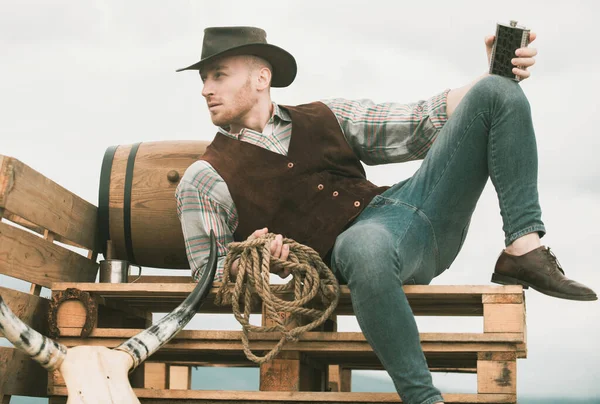 牛仔在农场里穿着牛仔帽和复古服装的英俊男子 喝威士忌的家伙 — 图库照片