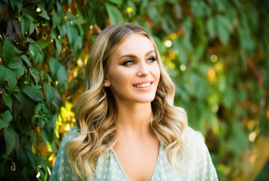 Portrait of a young woman, close up face of beautiful woman in park outdoor. Woman with romantic smile. Cheerful female model