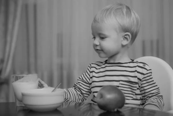 婴儿营养 吃健康的 小孩在吃点心 喝牛奶 孩子们拿着一杯牛奶 可爱的小男孩端着盘子和食物坐在桌旁 健康食品 健康的营养 男孩可爱的婴儿吃早餐 — 图库照片