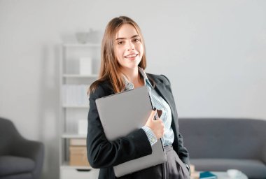 Güzel gülümseyen iş kadını bilgisayarında bilgisayar kullanıyor, ofiste internette sörf yapıyor.