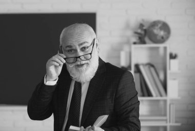 Tahtanın yanındaki sınıfta öğretmen bir ders öğretiyor. Üniversitede bir ders veriyor.