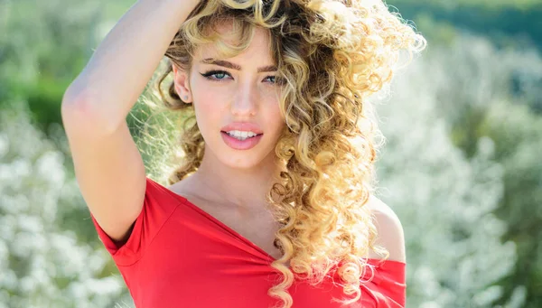 Blonde with curly hairstyle and red lips. Beautiful model with curly hair. Fashion haircut. Trendy haircuts