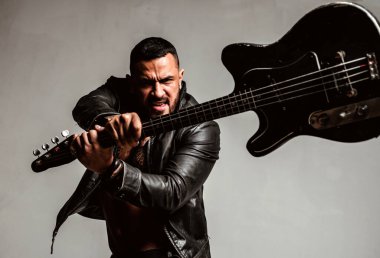 Agresif sinirli adam gitarı kırıyor. Duygular, saldırganlık, müzik aletleri. Rock konserinde gitarist. Elektro gitarlı bir müzisyen. Gitarist gitarı kırdı