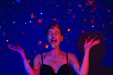 Konfeti üfleyen seksi kız. Doğum gününde, sevgililer gününde güzel bir genç kadının portresi. Seksi kız doğum gününde ışıltı saçar. Doğum gününü kutlayan şehvetli kadın. Sevgililer günün kutlu olsun. Doğum günü partisi