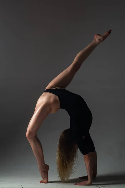 足の分割 柔軟な女の子はストレッチ体操を行います 美しいセクシーな柔軟な女性はセクシーな柔軟な体を示しています 黒を背景に柔軟性が広がる 強い柔軟性の女性の体 — ストック写真