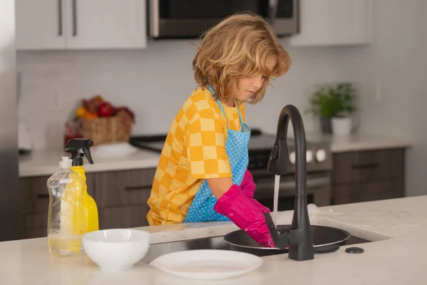 家事をする子供 子供は台所で料理をし 子供が家で掃除してる 家事をする子供は楽しい 台所で家事を手伝っているかわいい子供の男の子 — ストック写真