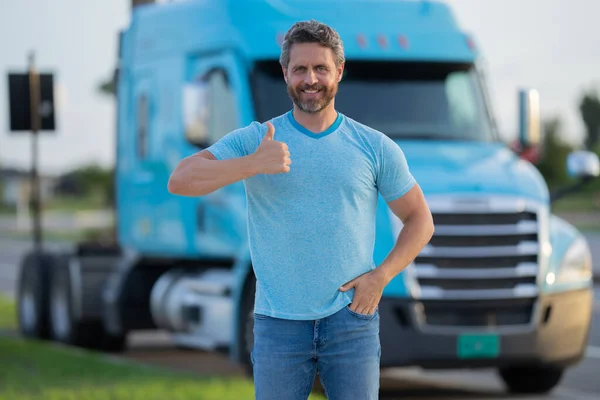 Men driver near lorry truck. Man owner truck driver in t-shirt near truck. Handsome middle aged man trucker trucking owner. Semi trailer, semi trucks. Handsome man posing in front of truck