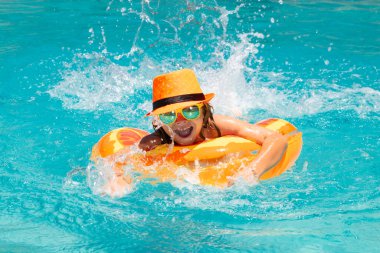 Çocuk havuzda oynuyor. Yaz tatili kavramı. Yaz çocukları plajdaki deniz suyunda yüzen yüzükle portre yaparlar.