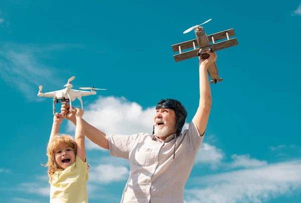 Grandfather and grandson with toy plane and quadcopter drone against sky. Child pilot aviator with plane dreams of traveling. Family Relationship Grandfather and child