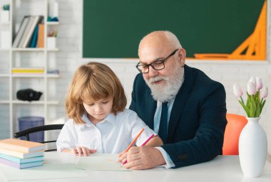 Okuldaki mutlu çocuk. Öğretmenin öğrenmesine yardım et. Eğitim, öğretmenlik, ilkokul.