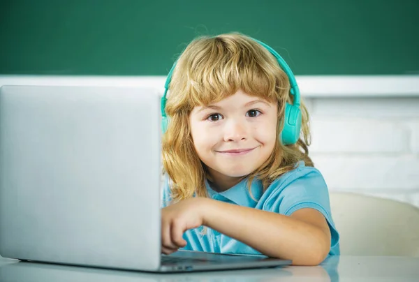 面白いです小学生男の子とともにラップトップコンピュータとヘッドフォンでクラスで学校 — ストック写真