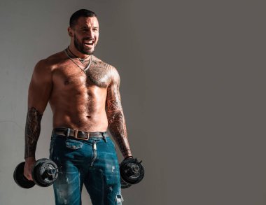 Dumbbell 'ın yanındaki adam. Vücut geliştiren kas geliştiren adam egzersiz yapıyor. Çıplak gövdeli kaslı seksi adam dambılla poz veriyor. Fitness konsepti. Erkek iri kıyım.