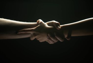 Eller siyah arka planda hareket ediyor. Yardım eli uzatıyorum. Destek ve yardım, kurtuluş. Kurtarma sırasında iki kişinin güçlü ve güçlü görüntüsü. Kurtuluşa uzanan ellere yardım ediyorum. Sıkı tutun.
