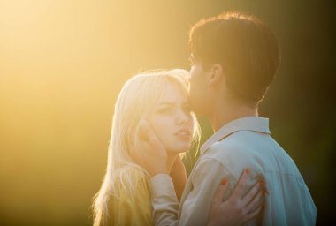 Gün batımında sarılıp öpüşen aşıklar. Birbirine aşık güzel bir çiftin portresi. Genç şehvetli kız arkadaşı, erkek arkadaşından tutkulu bir öpücük aldığı için mutlu. Yakışıklı genç adam kadınını kucaklıyor ve öpüyor.