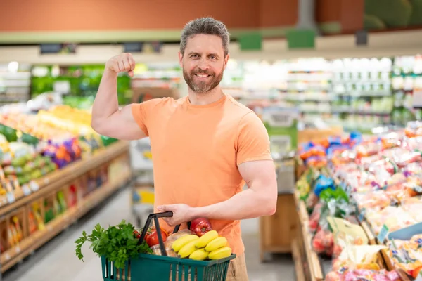 Handsome man with shopping basket with grocery. Man buying groceries in supermarket. Male model in shop. Concept of shopping at supermarket. Shopping with grocery cart at grocery store