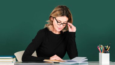 Üniversite sınıfında dizüstü bilgisayarı olan güzel bir genç kızın portresi. Sarışın, güzel kız öğrenci çalışıyor. Tahtada üniversite öğrencisi. Masadaki kız öğrenci. Öğrenci Günü