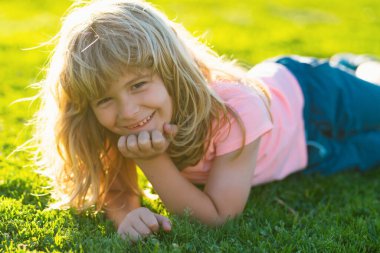 Yaz çocuğu suratı. Çimen geçmişi olan gülümseyen çocuk. Mutlu bir çocukluk. Çimenlerde yatan çocuk. Sahada yazın tadını çıkaran tatlı bir çocuk. Rüya gören çocuklar konsepti