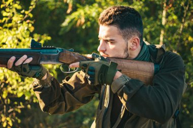 Avcı ormanda tüfek doğrulttu. Avcı avda av tüfeği tabancası ile. Bahar ormanında avlanmak. İzini takip et