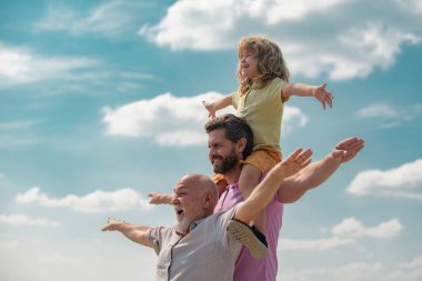 Çocuklarla aktif aile eğlencesi. Oğlu babası ve dedesi olan çocuk el kaldırıyor ya da yaz mevsiminde gökyüzünde uçan kollarını açıyor. Başlangıç, yaratıcılık başlangıç konsepti