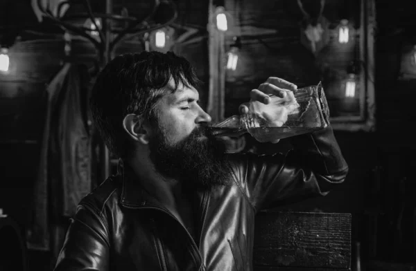 Sipping whiskey. Degustation, tasting. Portrait of a handsome man with beard. Brutality and masculine concept. Man with beard, biker in leather jacket. Portrait of stylish man beard. Vintage
