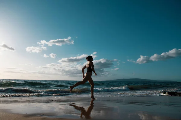 女は海岸を走る 休暇中に熱帯のビーチで海によって実行されているスポーティガール 夏休みのフィットネスと健康的なライフスタイル — ストック写真