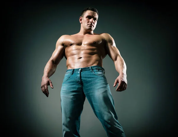 Sexy muscle strong face guy in jeans on gray isolated background