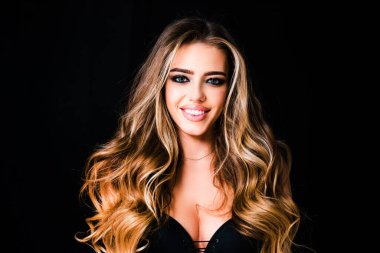 Uzun, pürüzsüz, düz saçlı güzel bir kadın. Uzun kıvırcık saçlı, sarışın bir kadın. Siyah arka planda gülümseyen güzel bir kadının güzel portresini kapat.