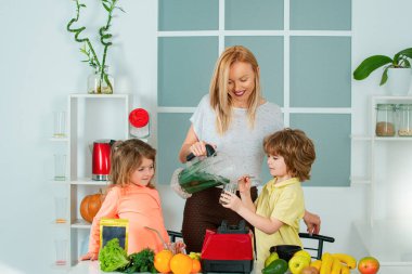 Anne kız ve oğlu mutfakta bir smoothie hazırlıyorlar. İyi eğlenceler ve sebzelerle oynayın. Sağlıklı beslenme ve çocuklar için yaşam tarzı. Vejetaryen beslenmesi ve sağlıklı bir yaşam tarzı. Mutlu sevgi dolu aile