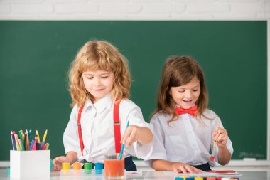 Children girl and boy drawing with coloring pens. Cute school kids painting in class at school. Painting lesson, drawing art. Early childhood education