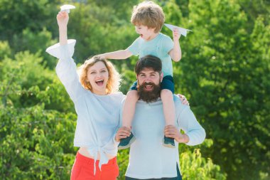 Mutlu aile ve küçük oğlu mavi gökyüzünde oynuyorlar. Baba, anne ve oğul parkta. Mutlu aile gülümsemesi ve kucaklaşması. Baba, anne ve bebek dışarıda birlikte oynuyorlar.