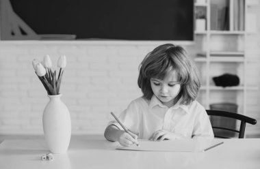 Okul çocuğu ödevini yapıyor. Okul çocuğu yeşil karatahtaya karşı. Okul için hazırlanıyor.