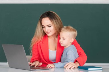 Anne ve oğul öğreniyor. İlkokul öğretmeni ve öğrenci online olarak sınıfta dizüstü bilgisayar kullanarak Webinar öğreniyor. Anne ve oğlu birlikte bilgisayar laptopu kullanıyorlar.