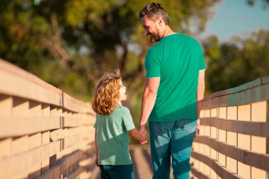 Baba ve Oğul 'un ağaçlık köprüde yürüdüğü arka manzara. Baba oğul konuşuyor, doğada eğleniyorlar. Ebeveynlik, ebeveynlik, çocukluk ve aile hayatı kavramı