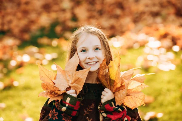 美しい公園に紅葉の良い女の子 幸せな子供の女の子が笑って 秋の屋外で葉を再生します 秋の公園で遊ぶ幸せな子供たち — ストック写真
