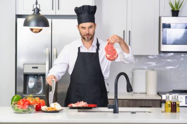 Modern mutfakta yemek pişiren adam. Adam evde ev işi yapıyor, mutfakta kahvaltı hazırlıyor. Yakışıklı adam mutfakta yemek pişiriyor. İspanyol adam mutfakta sağlıklı yemek pişiriyor.