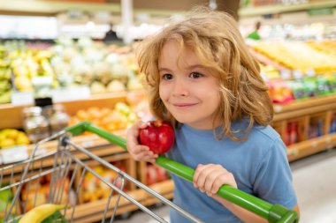 Alışveriş, indirim, satış konsepti. Alışveriş sepetli çocuk. Dükkandaki çocuk. Süpermarket ve market konsepti. Süpermarketten ürün alan küçük çocuk müşteriler