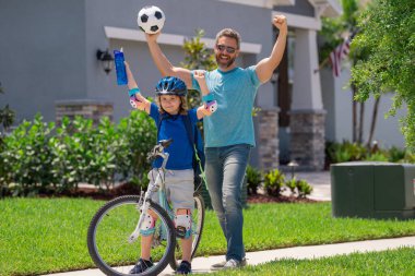 Sportif aile. Kazanan jest ile heyecanlı baba ve oğul. Babalar günün kutlu olsun. Baba oğluna bisiklete binmeyi öğretiyor. Baba küçük oğluna bisiklet sürmeyi öğretiyor. Babalar Günü konsepti