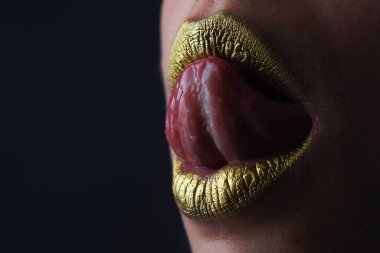 Dil yalayan dudaklar. Şehvetli bir ağız. Altın rujdaki öpücüğün sembolü. Cazibeli altın ağızlı. Dudaklarında altın boya var. Altın dudaklar, şehvetli kadın ağzı. Metalik gövde. Altın kavram